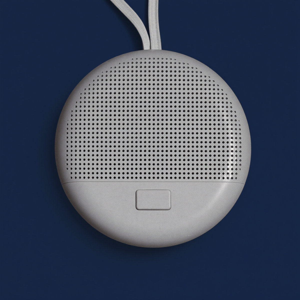 The NUNI Sound Machine — round white portable white noise machine with a dot-pattern speaker grille and wrist strap